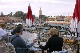 Image du Maroc Professionnelle de  Quelques touristes sont  installés avec leur verre de thé à la menthe sur la terrasse de l'hôtel café de France, la vue donnant sur la fameuse place Jemaa El Fana de Marrakech, Dimanche 27 Février 2005, au fond le minaret de la Koutoubia. (Photo / Abdeljalil Bounhar) 